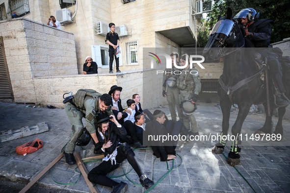 Israeli police officers intervene in Ultra-Orthodox Jews, also known as Haredim, who gather to stage a protest against mandatory military se...