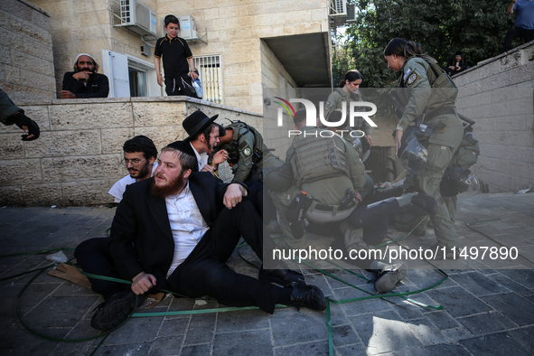 Israeli police officers intervene in Ultra-Orthodox Jews, also known as Haredim, who gather to stage a protest against mandatory military se...