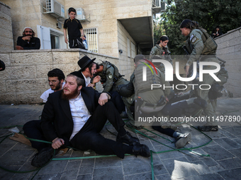 Israeli police officers intervene in Ultra-Orthodox Jews, also known as Haredim, who gather to stage a protest against mandatory military se...