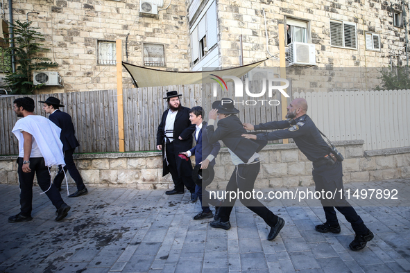 Israeli police officers intervene in Ultra-Orthodox Jews, also known as Haredim, who gather to stage a protest against mandatory military se...