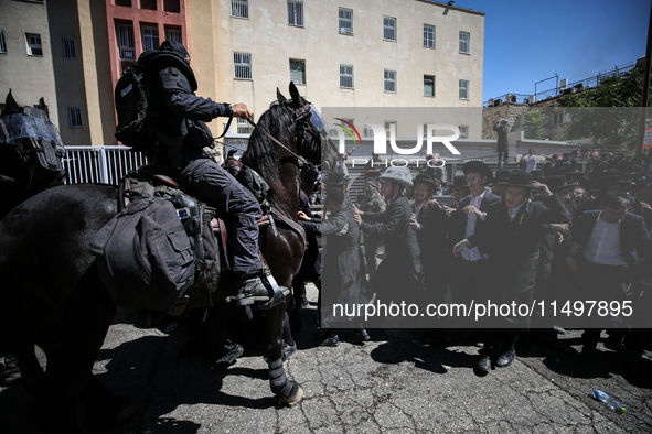 Israeli police officers intervene in Ultra-Orthodox Jews, also known as Haredim, who gather to stage a protest against mandatory military se...