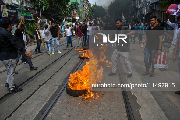 Supporters of the Congress party burn a tire in protest against the rape and murder of a junior doctor in Kolkata, India, on August 21, 2024...