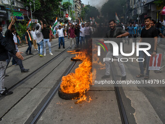 Supporters of the Congress party burn a tire in protest against the rape and murder of a junior doctor in Kolkata, India, on August 21, 2024...