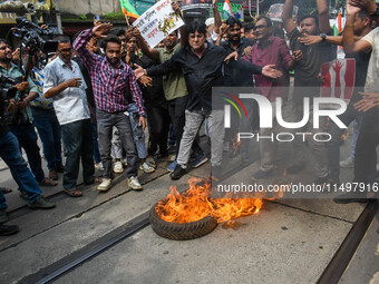 Supporters of the Congress party burn a tire in protest against the rape and murder of a junior doctor in Kolkata, India, on August 21, 2024...