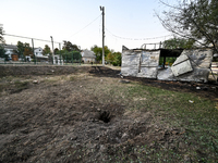 A hole from a Russian artillery shell strike is in the ground near the Levada children's cafe in the central park in Malokaterynivka village...