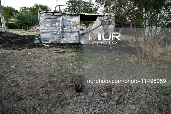 A hole from a Russian artillery shell strike is in the ground near the Levada children's cafe in the central park in Malokaterynivka village...