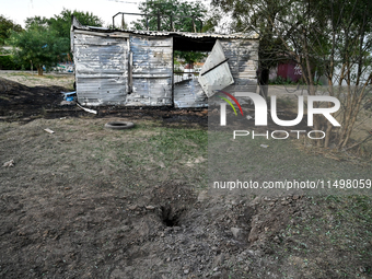 A hole from a Russian artillery shell strike is in the ground near the Levada children's cafe in the central park in Malokaterynivka village...