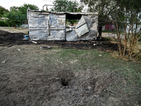 A hole from a Russian artillery shell strike is in the ground near the Levada children's cafe in the central park in Malokaterynivka village...