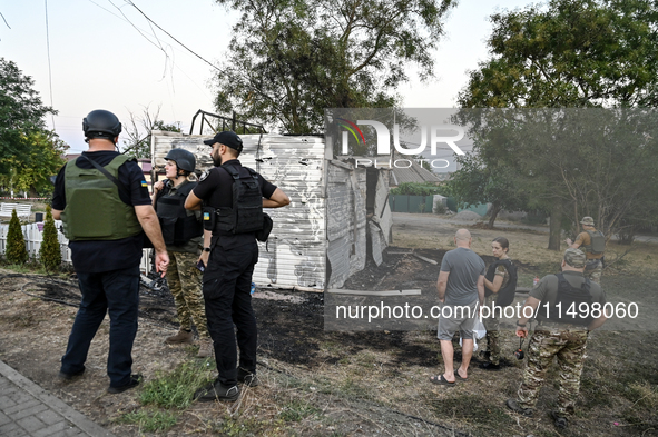 Law enforcers are outside the Levada children's cafe in the central park damaged by a Russian artillery shell strike in Malokaterynivka vill...