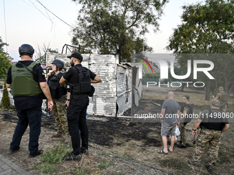 Law enforcers are outside the Levada children's cafe in the central park damaged by a Russian artillery shell strike in Malokaterynivka vill...