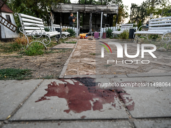 A blood stain of one of the children wounded by a Russian artillery shell strike on the Levada cafe is on the ground in the central park in...