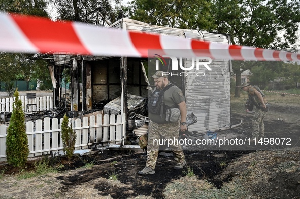 Law enforcers are outside the Levada children's cafe in the central park damaged by a Russian artillery shell strike in Malokaterynivka vill...