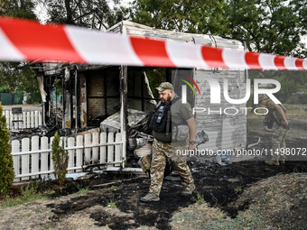 Law enforcers are outside the Levada children's cafe in the central park damaged by a Russian artillery shell strike in Malokaterynivka vill...