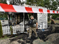 Law enforcers are outside the Levada children's cafe in the central park damaged by a Russian artillery shell strike in Malokaterynivka vill...