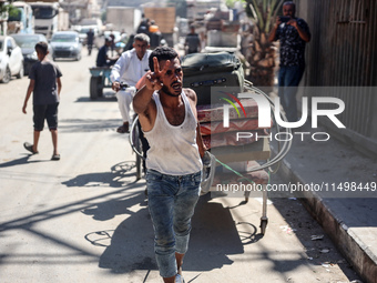 Palestinians flee with their belongings in Deir el-Balah, Gaza Strip, on August 21, 2024, amid the ongoing conflict between Israel and the H...