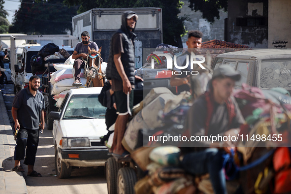 Palestinians flee with their belongings in Deir el-Balah, Gaza Strip, on August 21, 2024, amid the ongoing conflict between Israel and the H...