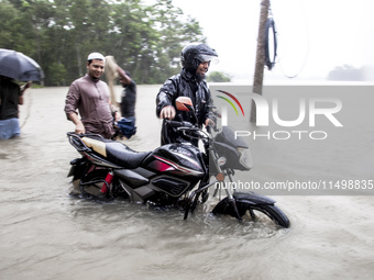 Pedestrians wade through floodwaters up to their waists and knees to safety in the Munsirhat area of Feni district in Chittagong Division, B...