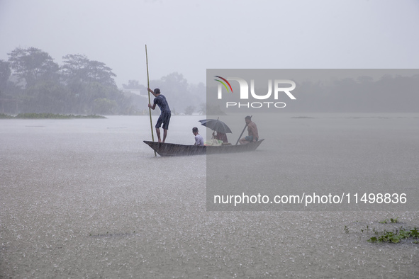 A family tries to reach safety by boat during heavy rains in the Munsirhat area of Feni district in Chittagong Division, Bangladesh, on Augu...