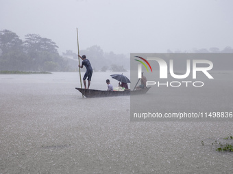 A family tries to reach safety by boat during heavy rains in the Munsirhat area of Feni district in Chittagong Division, Bangladesh, on Augu...