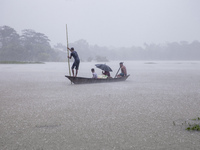 A family tries to reach safety by boat during heavy rains in the Munsirhat area of Feni district in Chittagong Division, Bangladesh, on Augu...