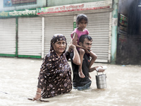 Pedestrians wade through floodwaters up to their waists and knees to safety in the Munsirhat area of Feni district in Chittagong Division, B...