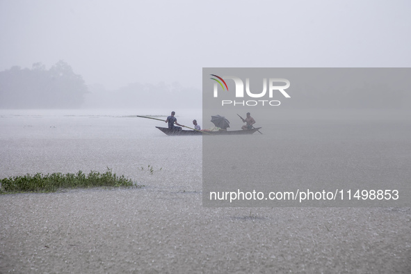 On August 21, 2024, in Feni, Bangladesh, a family tries to reach safety by boat during heavy rains in the Munsirhat area of Feni district in...