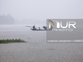 On August 21, 2024, in Feni, Bangladesh, a family tries to reach safety by boat during heavy rains in the Munsirhat area of Feni district in...