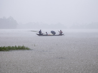 On August 21, 2024, in Feni, Bangladesh, a family tries to reach safety by boat during heavy rains in the Munsirhat area of Feni district in...