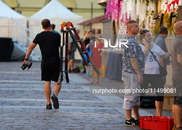 A man with a ladder and a drill is seen on the street in Krakow, Poland, on August 13, 2024. 