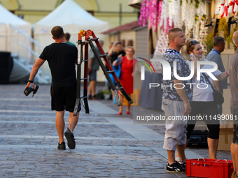 A man with a ladder and a drill is seen on the street in Krakow, Poland, on August 13, 2024. (