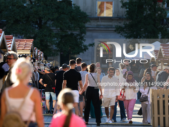 People at a handicraft fair are seen on the Main Market Square in Krakow, Poland, on August 13, 2024. (