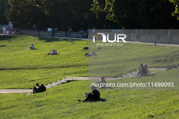 People spend their free time on the boulevards along the Vistula River in Krakow, Poland, on August 13, 2024. 