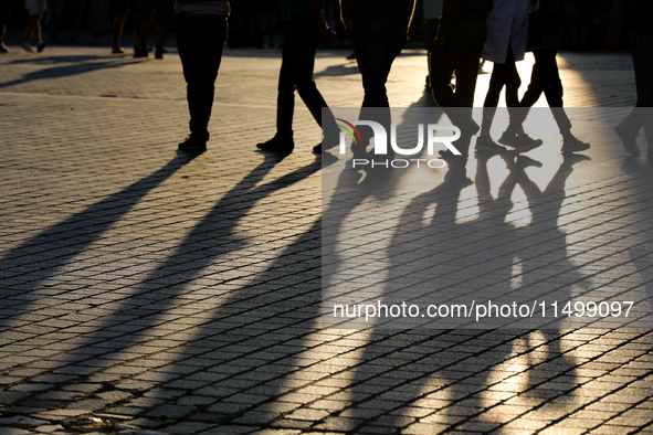 People during sunset are seen on the Main Square in Krakow, Poland, on August 13, 2024. 