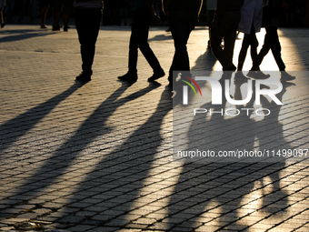 People during sunset are seen on the Main Square in Krakow, Poland, on August 13, 2024. (