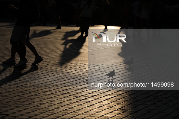 People during sunset are seen on the Main Square in Krakow, Poland, on August 13, 2024. 