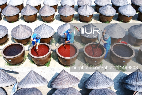 Workers use a wooden rake to turn sauces at the old soy sauce natural drying sauce shop in Yanhe Village, Rucheng Street, Rugao city, East C...