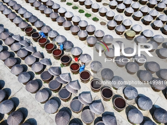 Workers use a wooden rake to turn sauces at the old soy sauce natural drying sauce shop in Yanhe Village, Rucheng Street, Rugao city, East C...