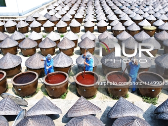 Workers use a wooden rake to turn sauces at the old soy sauce natural drying sauce shop in Yanhe Village, Rucheng Street, Rugao city, East C...