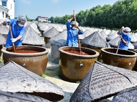 Workers use a wooden rake to turn sauces at the old soy sauce natural drying sauce shop in Yanhe Village, Rucheng Street, Rugao city, East C...