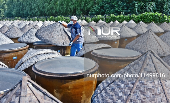 Workers use a wooden rake to turn sauces at the old soy sauce natural drying sauce shop in Yanhe Village, Rucheng Street, Rugao city, East C...