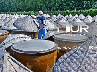 Workers use a wooden rake to turn sauces at the old soy sauce natural drying sauce shop in Yanhe Village, Rucheng Street, Rugao city, East C...