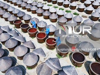 Workers use a wooden rake to turn sauces at the old soy sauce natural drying sauce shop in Yanhe Village, Rucheng Street, Rugao city, East C...