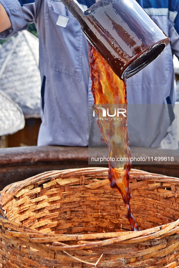 Workers use a wooden rake to turn sauces at the old soy sauce natural drying sauce shop in Yanhe Village, Rucheng Street, Rugao city, East C...