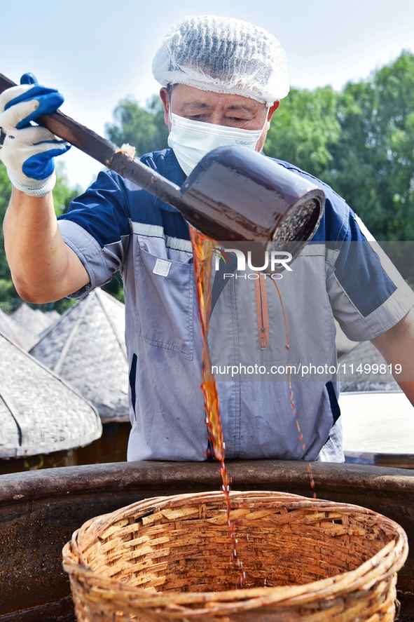 Workers use a wooden rake to turn sauces at the old soy sauce natural drying sauce shop in Yanhe Village, Rucheng Street, Rugao city, East C...