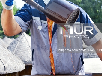 Workers use a wooden rake to turn sauces at the old soy sauce natural drying sauce shop in Yanhe Village, Rucheng Street, Rugao city, East C...