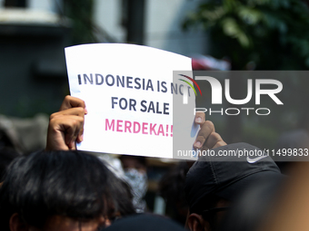 Students hold protest posters during a demonstration to reject the ratification of the Regional Head Election (Pilkada) Bill in front of the...