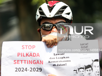 Students hold protest posters during a demonstration to reject the ratification of the Regional Head Election (Pilkada) Bill in front of the...