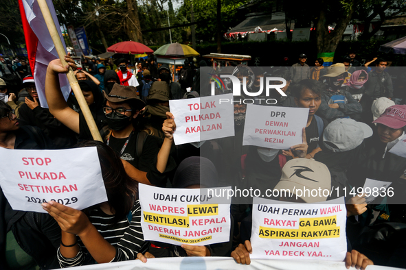 Students hold protest posters during a demonstration to reject the ratification of the Regional Head Election (Pilkada) Bill in front of the...