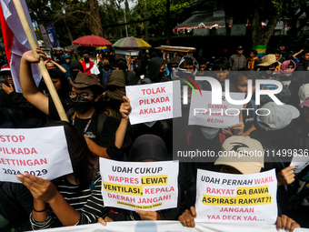 Students hold protest posters during a demonstration to reject the ratification of the Regional Head Election (Pilkada) Bill in front of the...