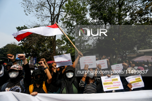 Students hold protest posters during a demonstration to reject the ratification of the Regional Head Election (Pilkada) Bill in front of the...